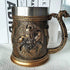 Decorative bronze mug with intricate designs on a white surface