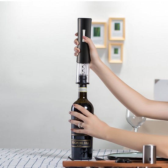 Black electric wine opener set by WoodyKitchenware with automatic corkscrew, foil cutter, and can opener, displayed on a wooden surface.