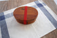 Round brown wooden bento box by WoodyKitchenware, traditional Japanese lunch box with a smooth wood finish and compact design.