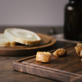 Round black walnut wood cutting board by WoodyKitchenware, showcasing a smooth, polished surface ideal for kitchen prep and serving.